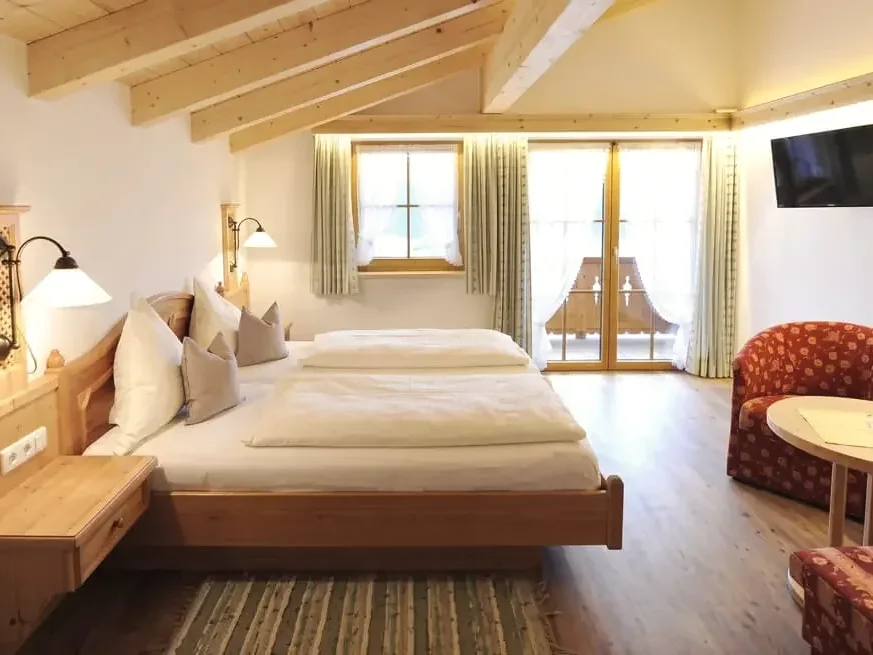 Doppelzimmer mit Holzmöbeln und Balkontür