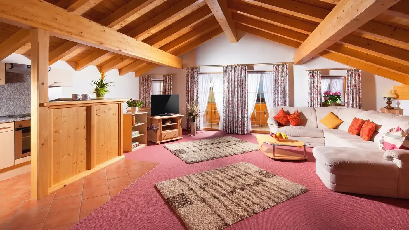 Wohnraum einer Ferienwohnung mit Couchecke, Essecke und Holzdecke