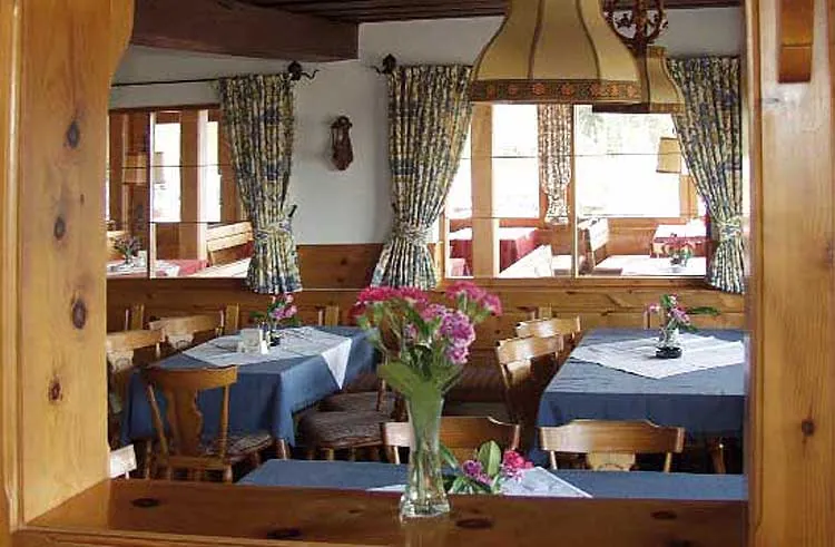 Gaststube mit gedeckten Tischen und Blick durch die Fenster